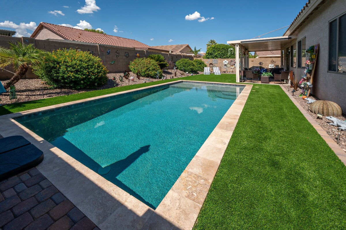 Finished rectangular pool with turf, pavers and a covered patio in an Arizona backyard