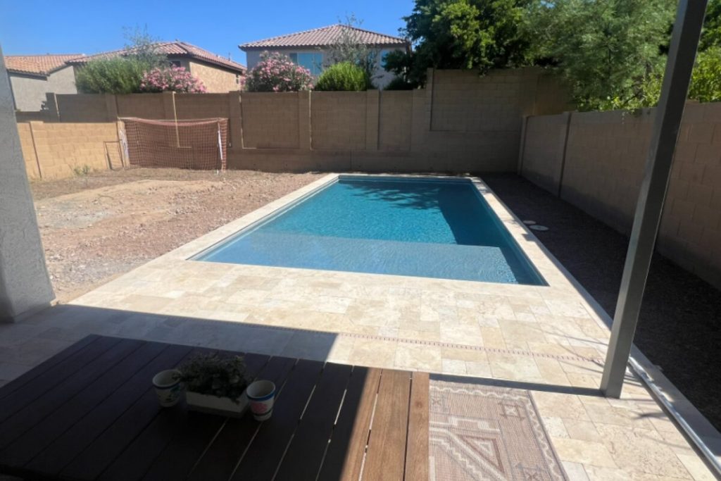 Newly built rectangular pool in an Arizona backyard with bare dirt and construction fencing still in place